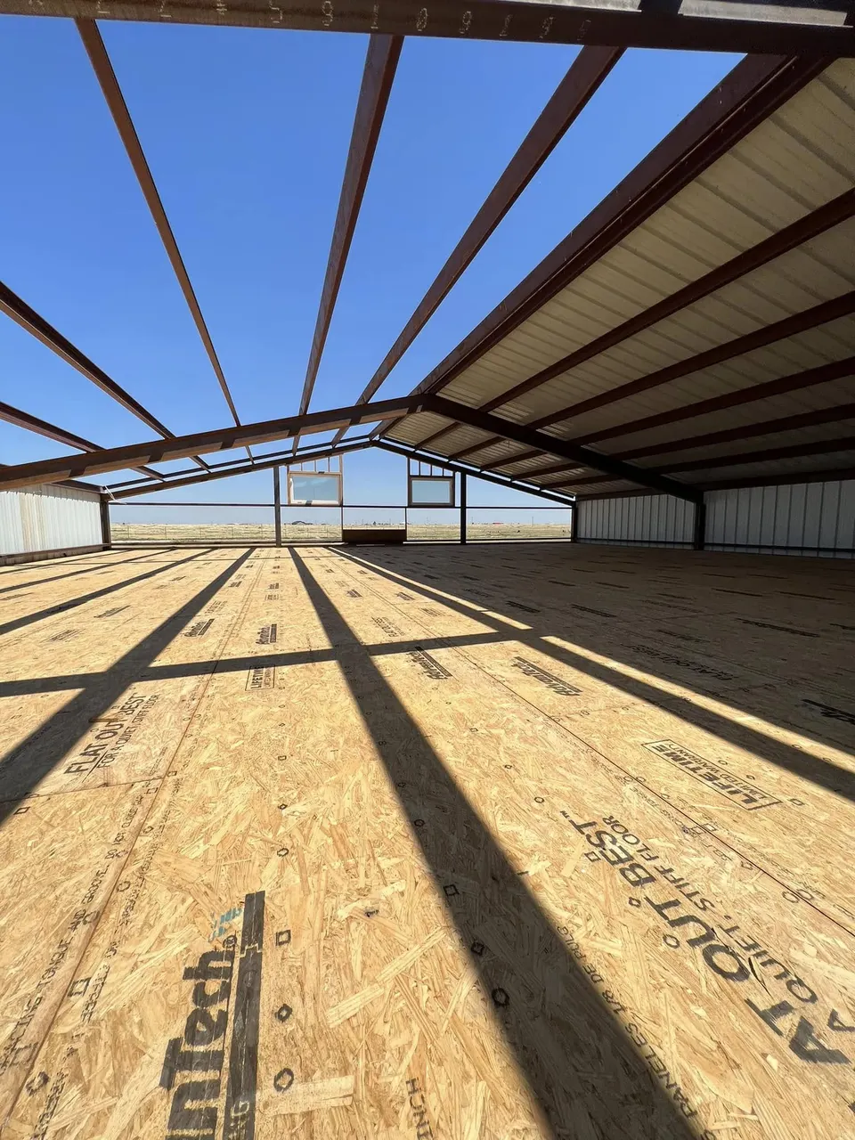 Interior of Homerun Fabrication steel building with red purlins and OSB subfloor
